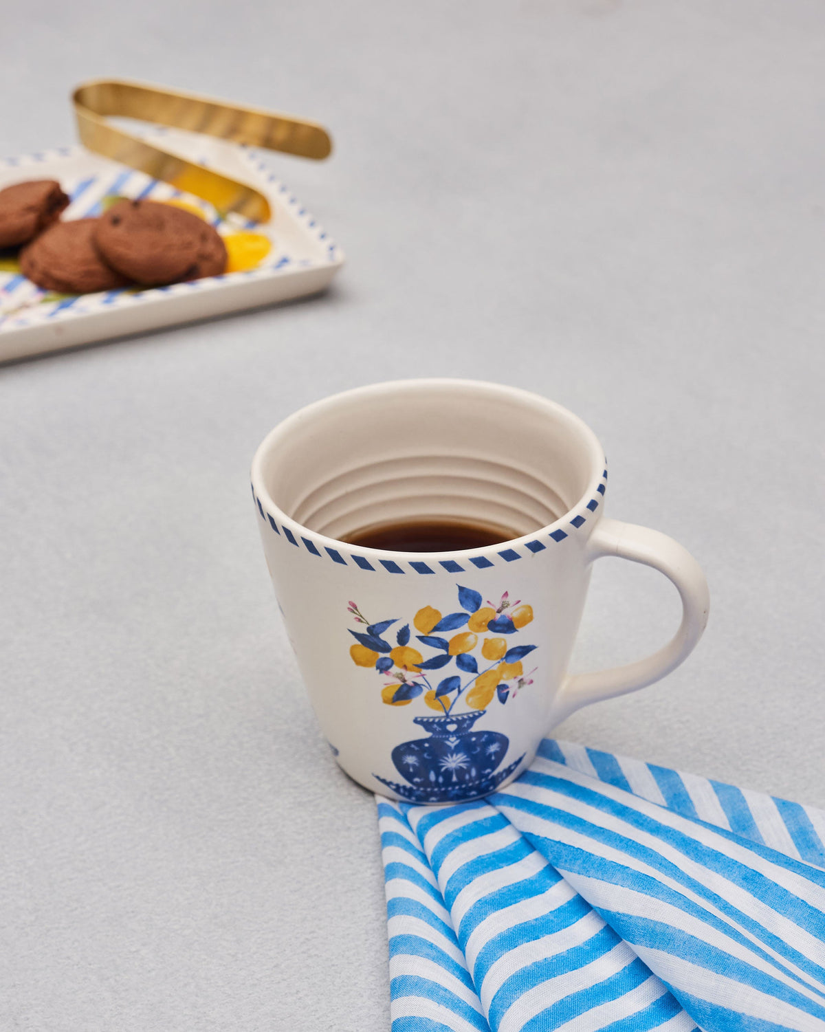 Asfar Conical Mug filled with coffee, showing its blue vase and lemon motif.