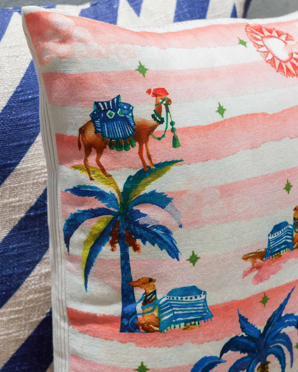 Close-up of the Sahara Striped Cushion Cover showing camels and palms on pink stripes.