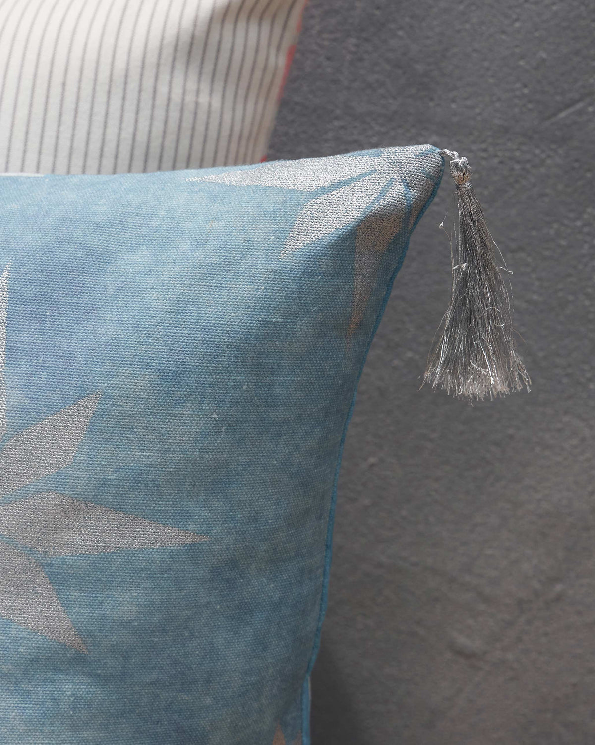 Close-up of Azraq Tile Cushion Cover showing a grey tassel at its corner.