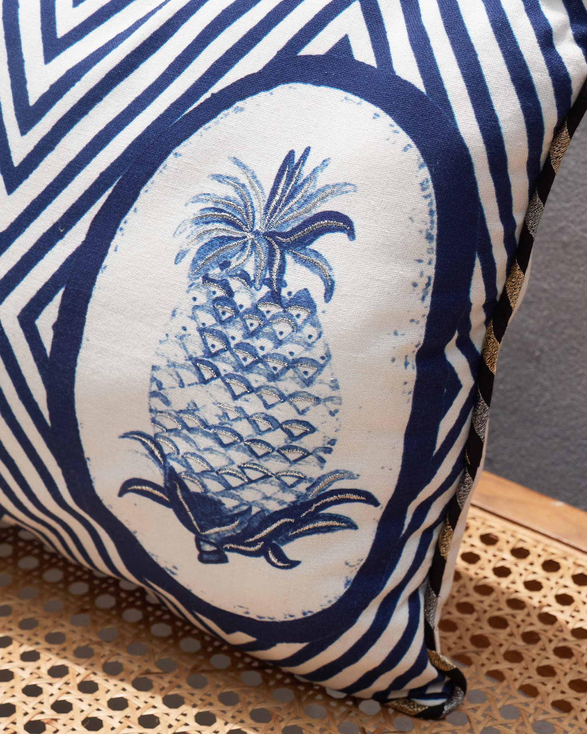 Close-up of a pineapple motif in an oval on the indigo lumbar cushion cover.