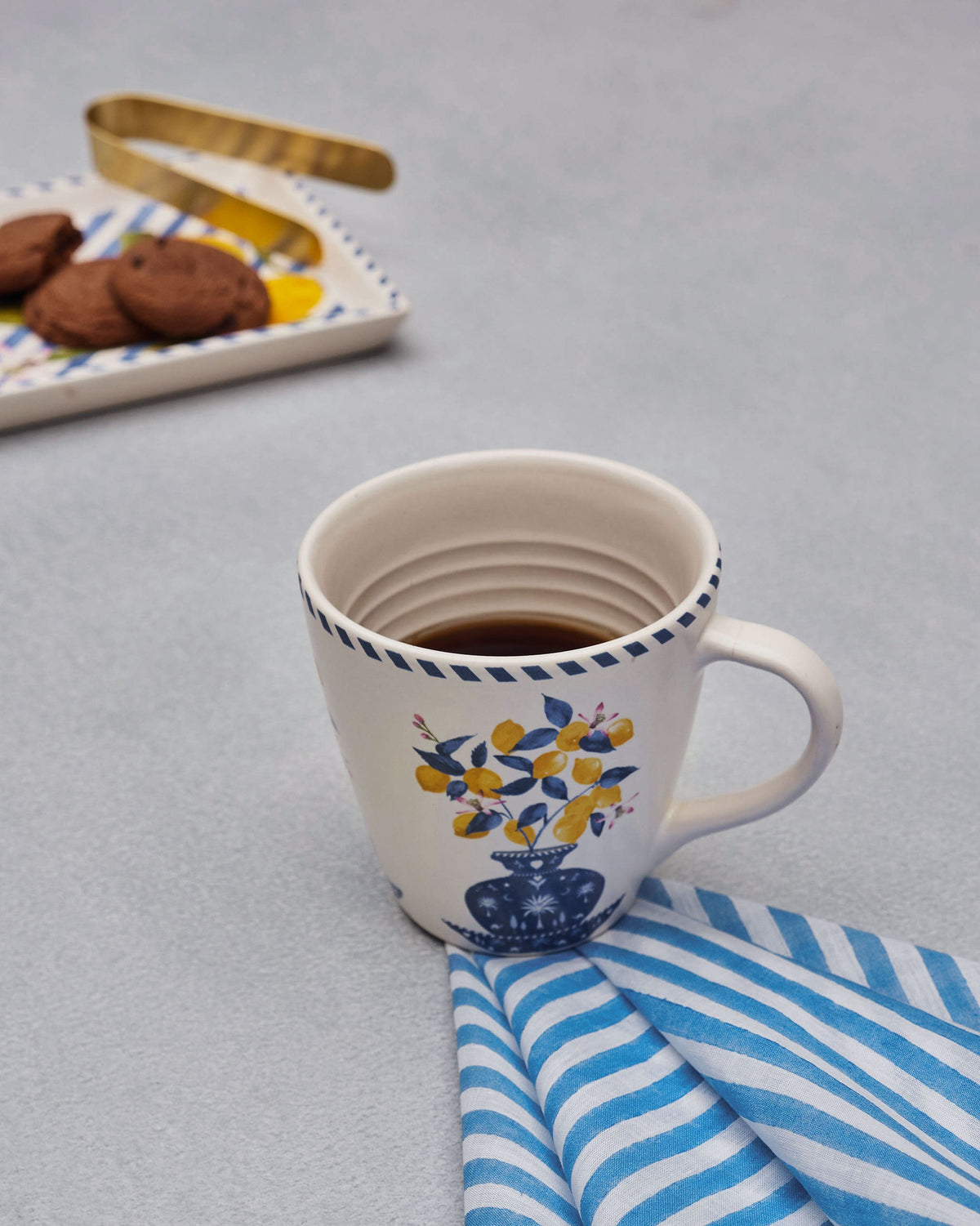 Azraq blue-striped napkin under a cream mug.