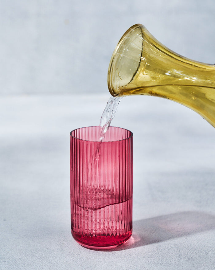 Serenity Highball Glass in pink being filled from a jug.