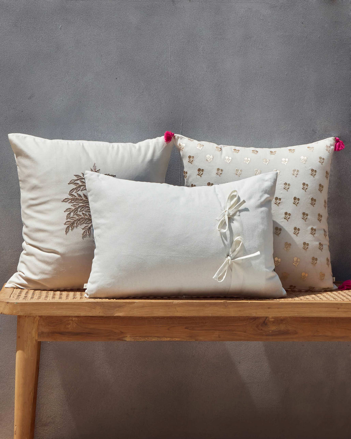 Whimsical Chanderi Lumbar in plain white with bow ties on a wooden bench.