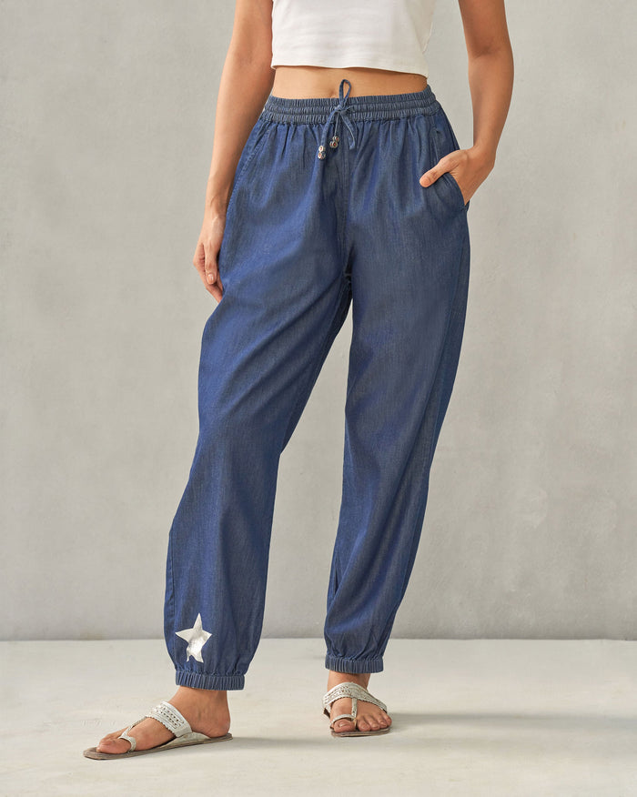 Person wearing denim Jogger Pants with a silver star at the ankle.