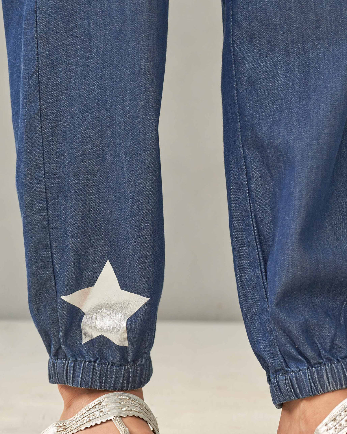 Close-up of a denim Jogger Pants ankle showing a silver star.