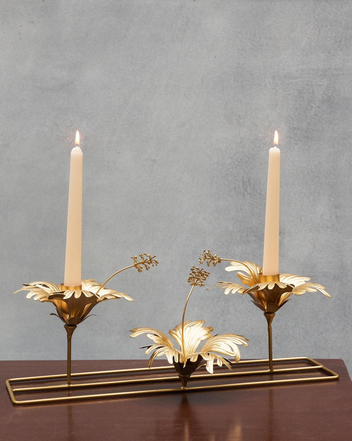 Two lit Twilight Tapered Candles - Set of 10 standing in gold holders.