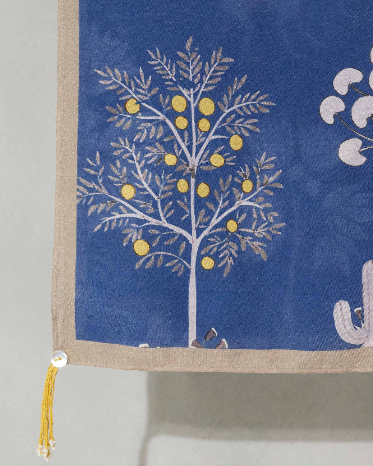 Close-up of a Willow Scarf corner showing a tree with yellow fruit and a yellow tassel.