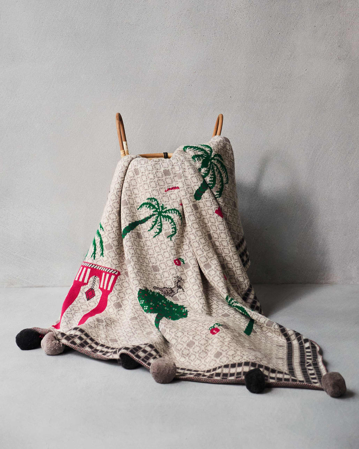 Mirage throw draped over a chair with palm trees and a spotted cat.
