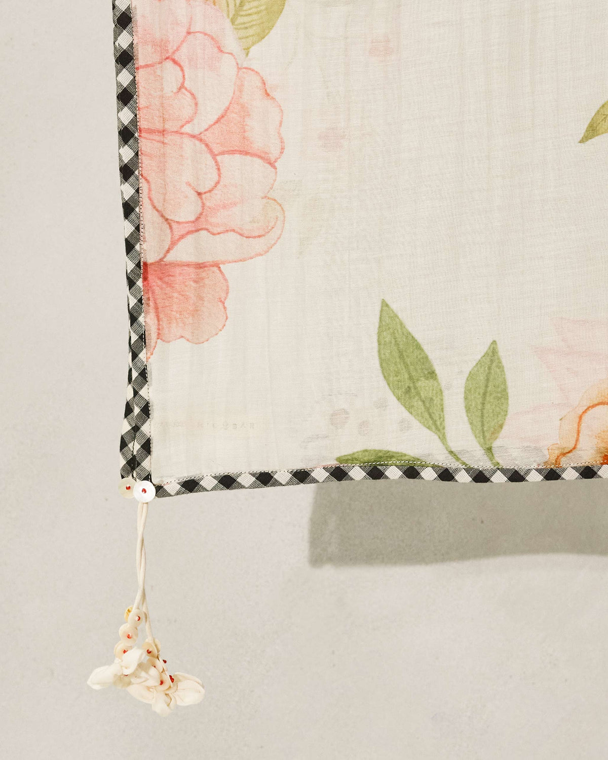 Close-up of an ivory Gul Dupatta corner showing pink blooms and a checked border.