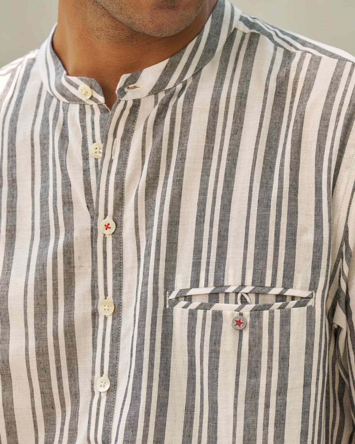 Close-up of an ivory and grey Pondicherry Shirt placket and chest pocket with a red star button.