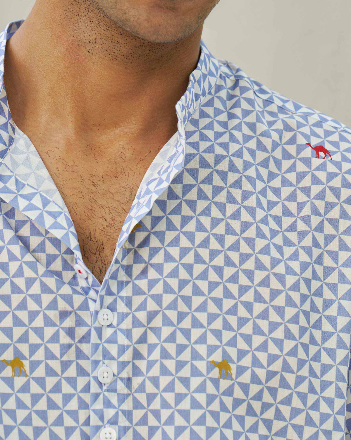 Close-up of a blue and white Angtak Shirt showing the embroidered camel motifs.