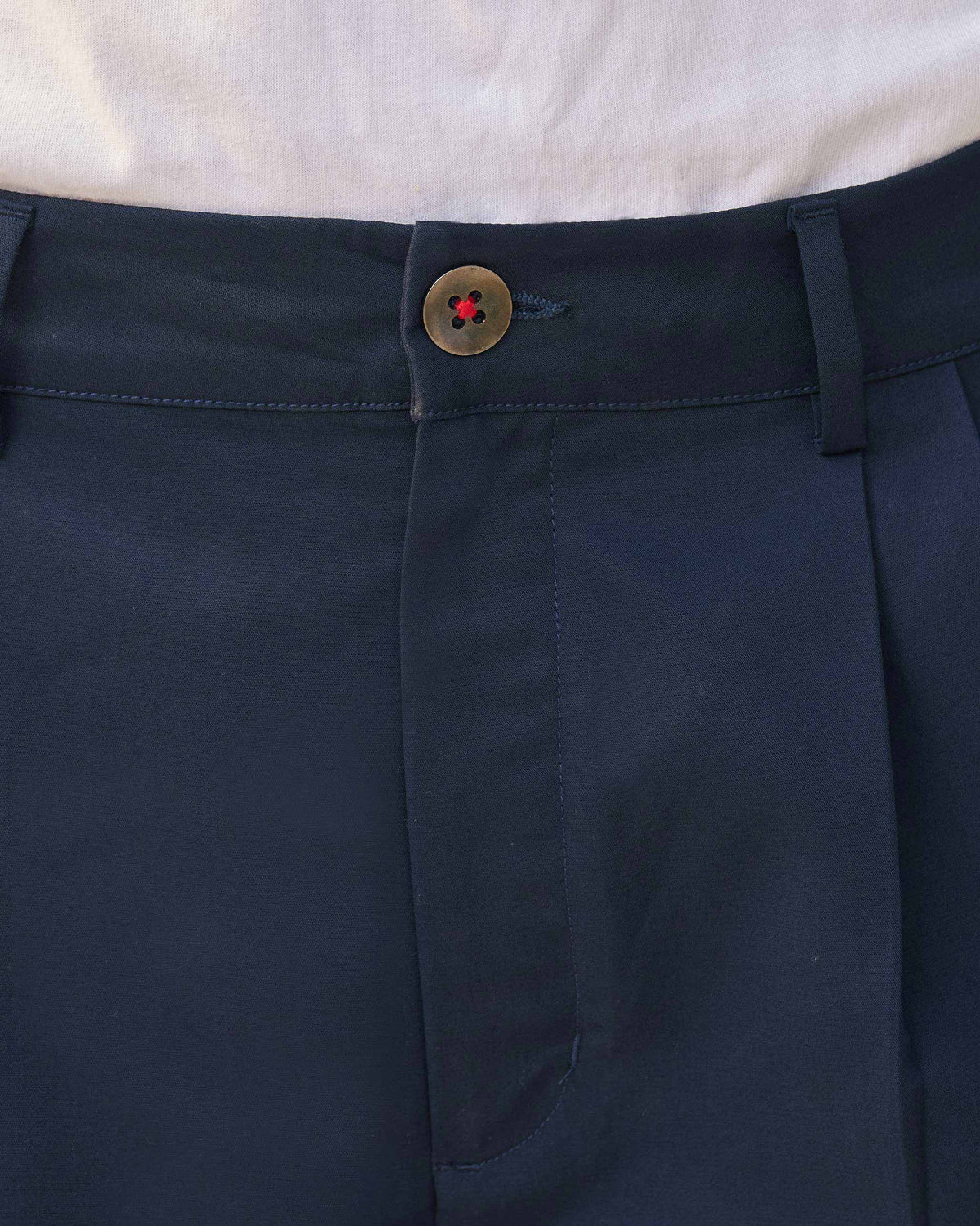 Close-up of navy Forty Trousers showing the waistband and a red-accented button.