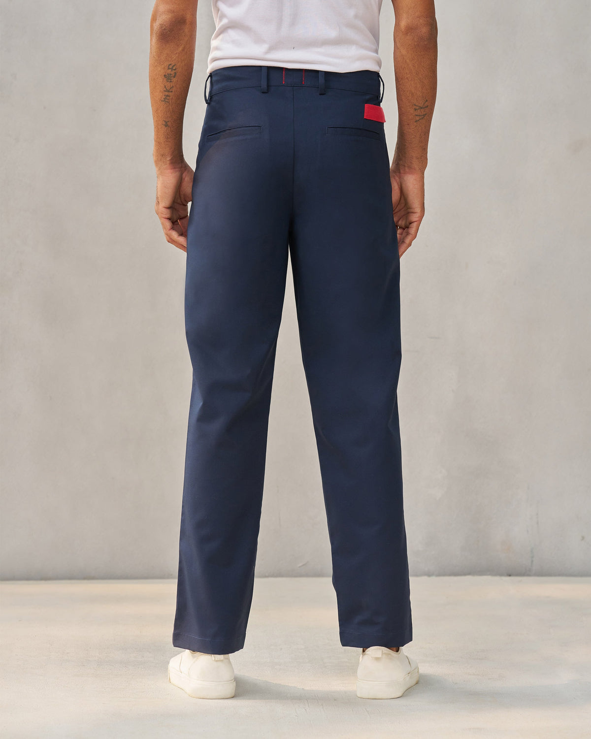 Back of navy Forty Trousers with red pocket trim worn by a person.