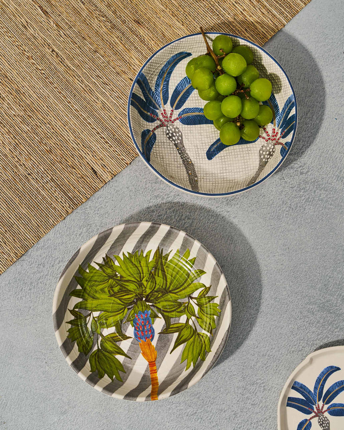 Overhead of Dancing Palm shallow bowls, one striped with a green palm and one blue with palm motifs.