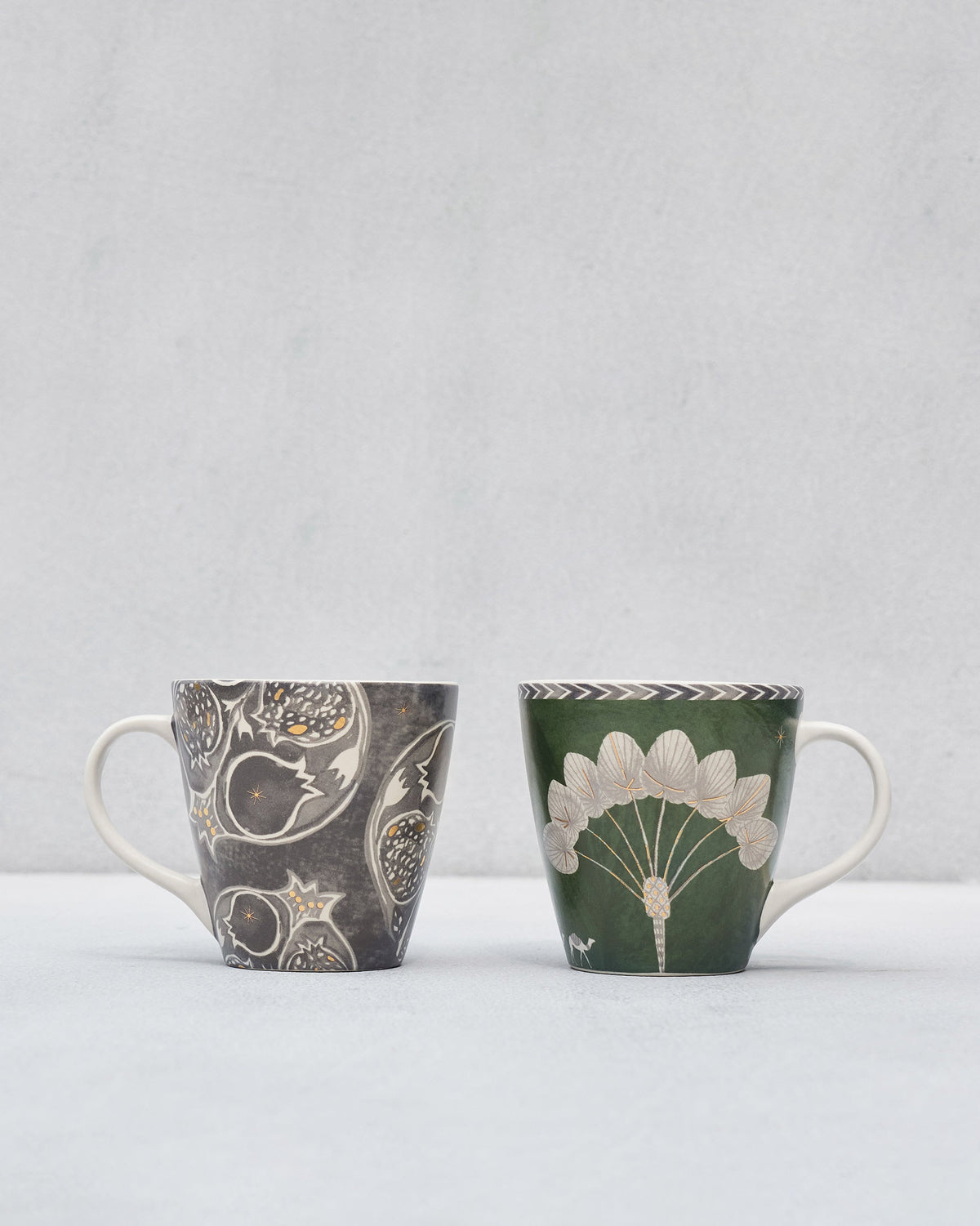 Anar Palm Conical Mugs, one charcoal with pomegranates and one green with a palm fan.