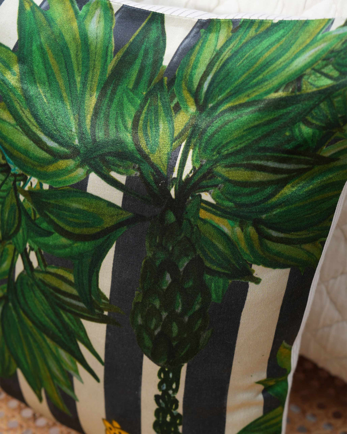 Close-up of Leopard Grove Cushion Cover showing green leaves over black and cream stripes.