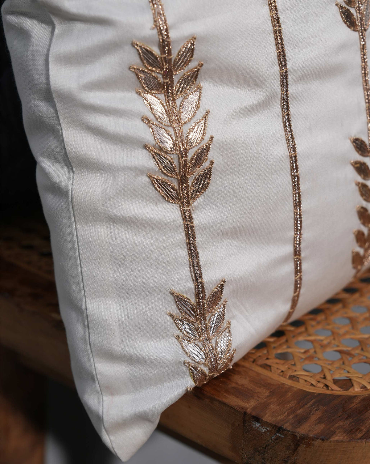 Close-up of the Shimmer Cushion Cover showing embroidered leaf stems along its front.