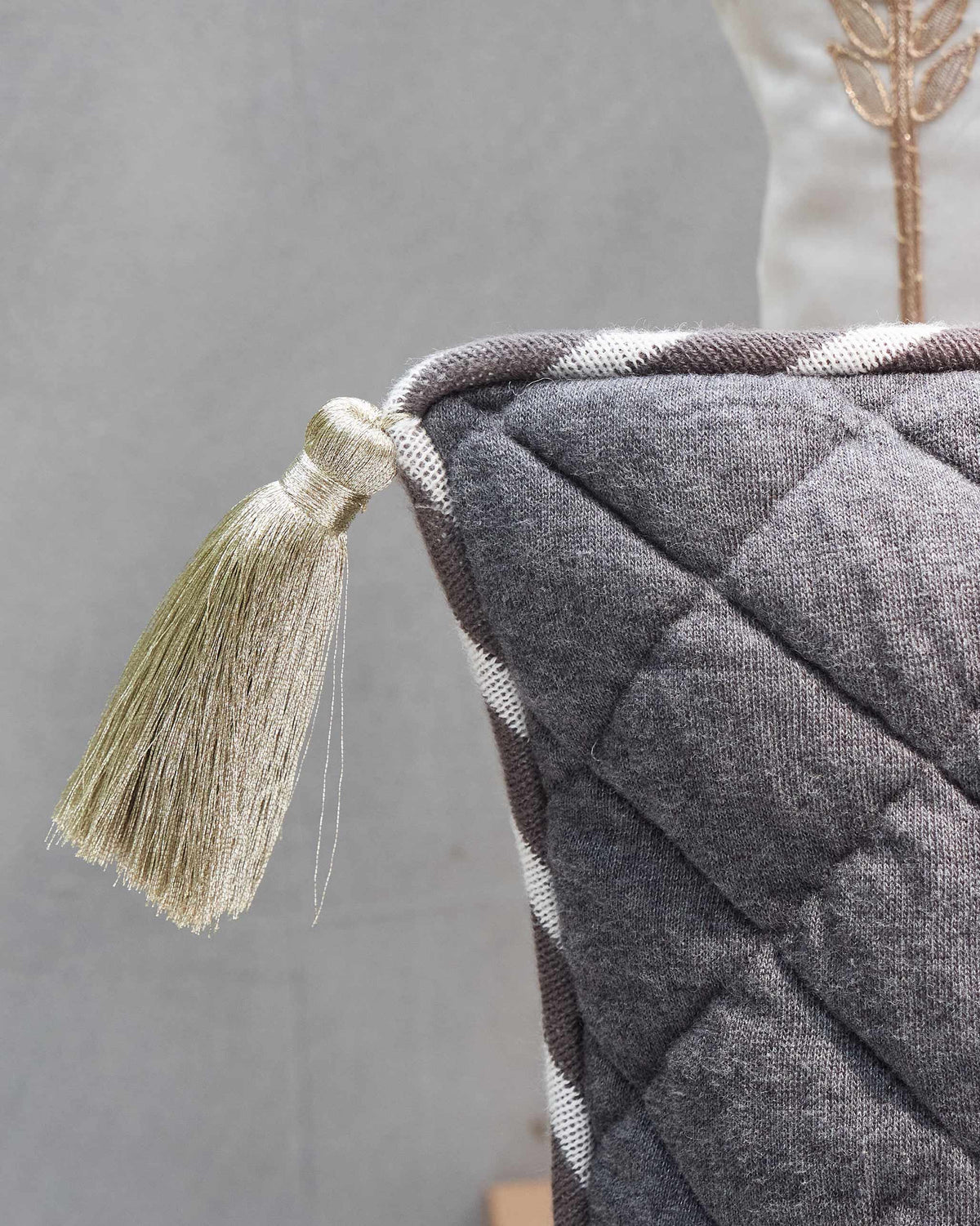 Close-up of a Sahara Tent Cushion Cover corner with a light olive tassel.