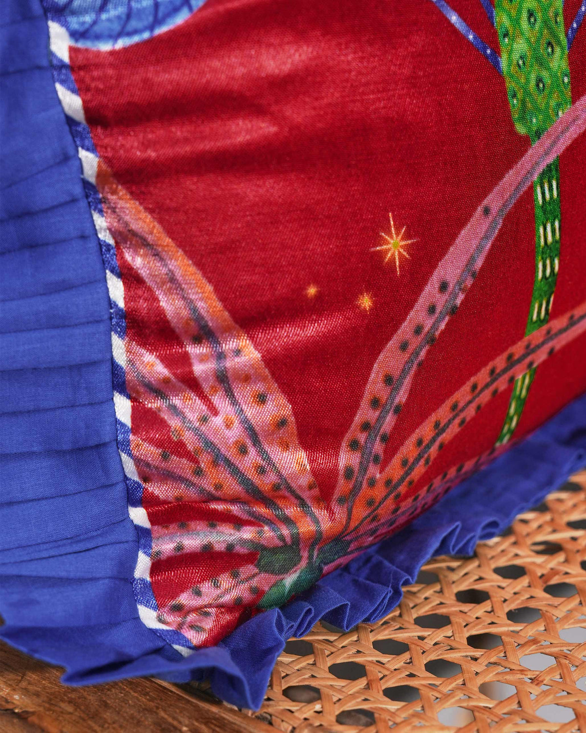 Close-up of Red desert Cushion Cover showing its blue pleated ruffle and white piping.