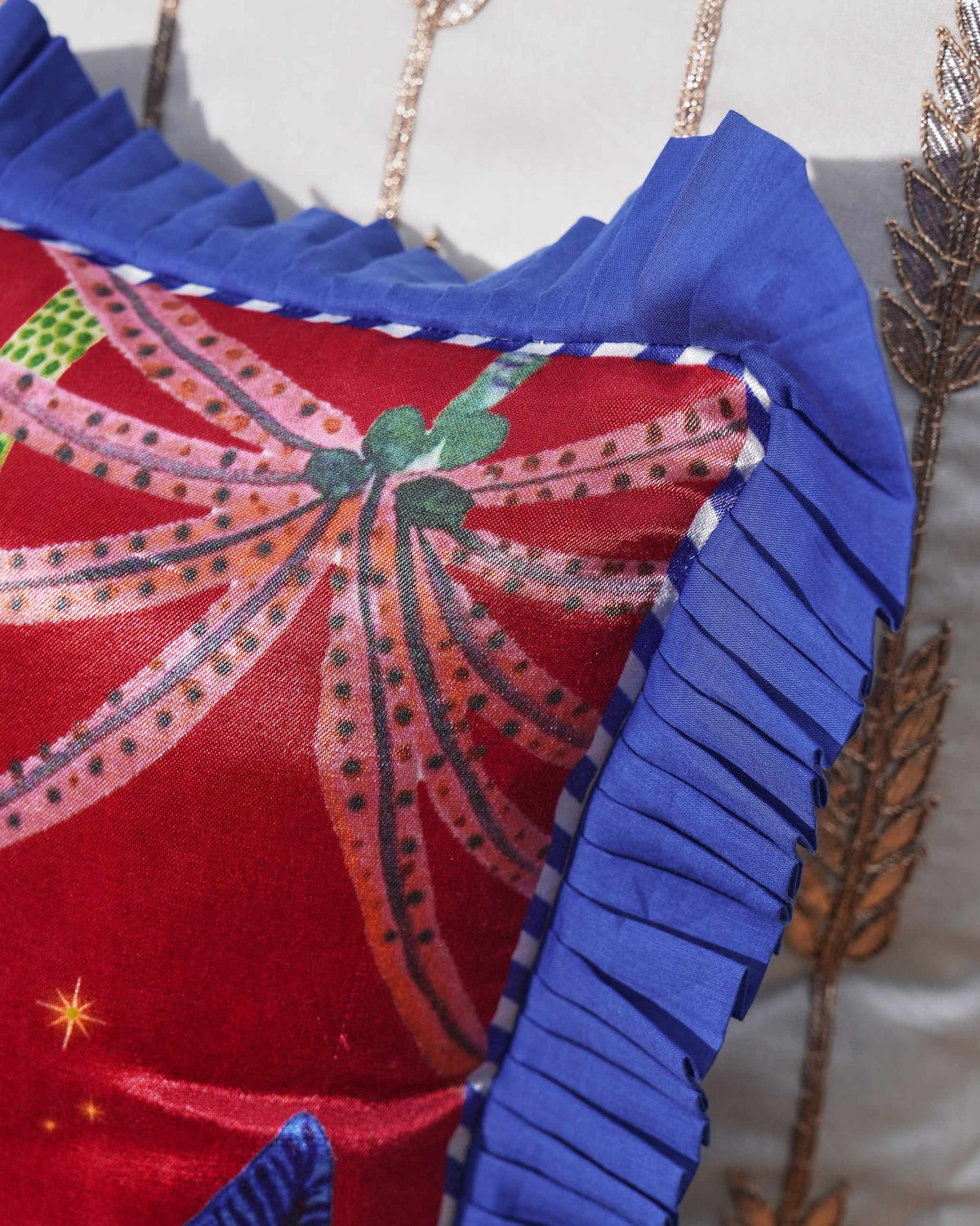 Close-up of a Red desert Cushion Cover corner with a pleated blue ruffle.