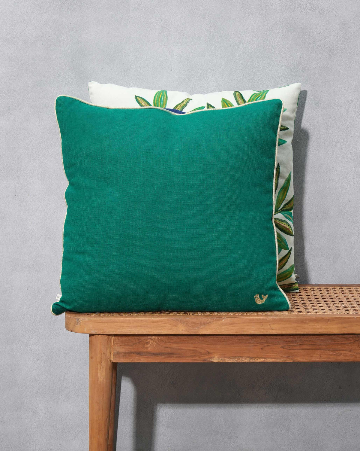 Close-up of the green Desert Lagoon Cushion Cover showing a gold bird on the corner.