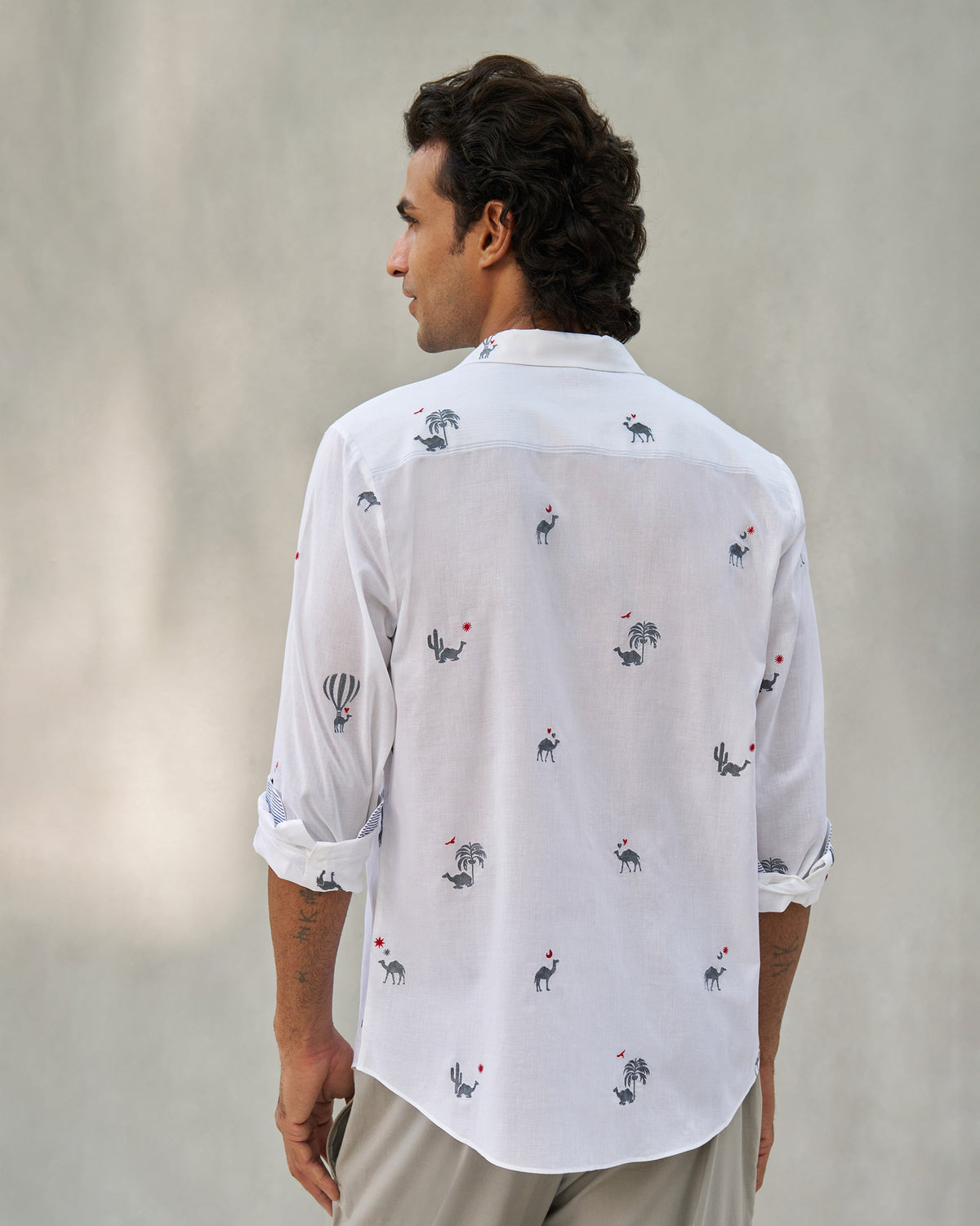 Back of a white Hakuna shirt with camel and palm motifs.