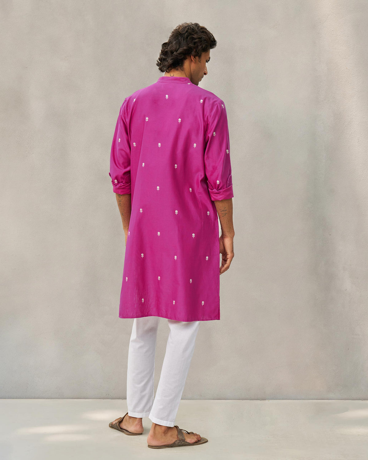 Back of a magenta neckband kurta with embroidered motifs worn by a person.