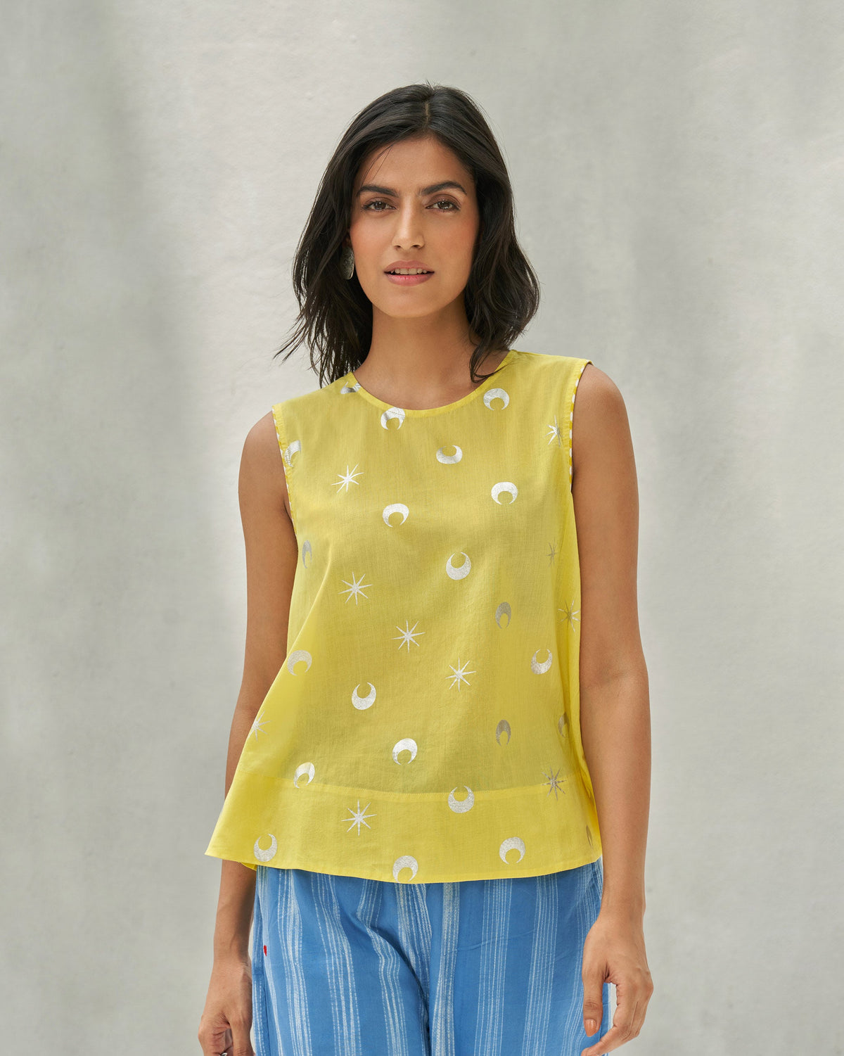 Person wearing a yellow Demi Moon Ruffle Top with silver moon and star motifs.