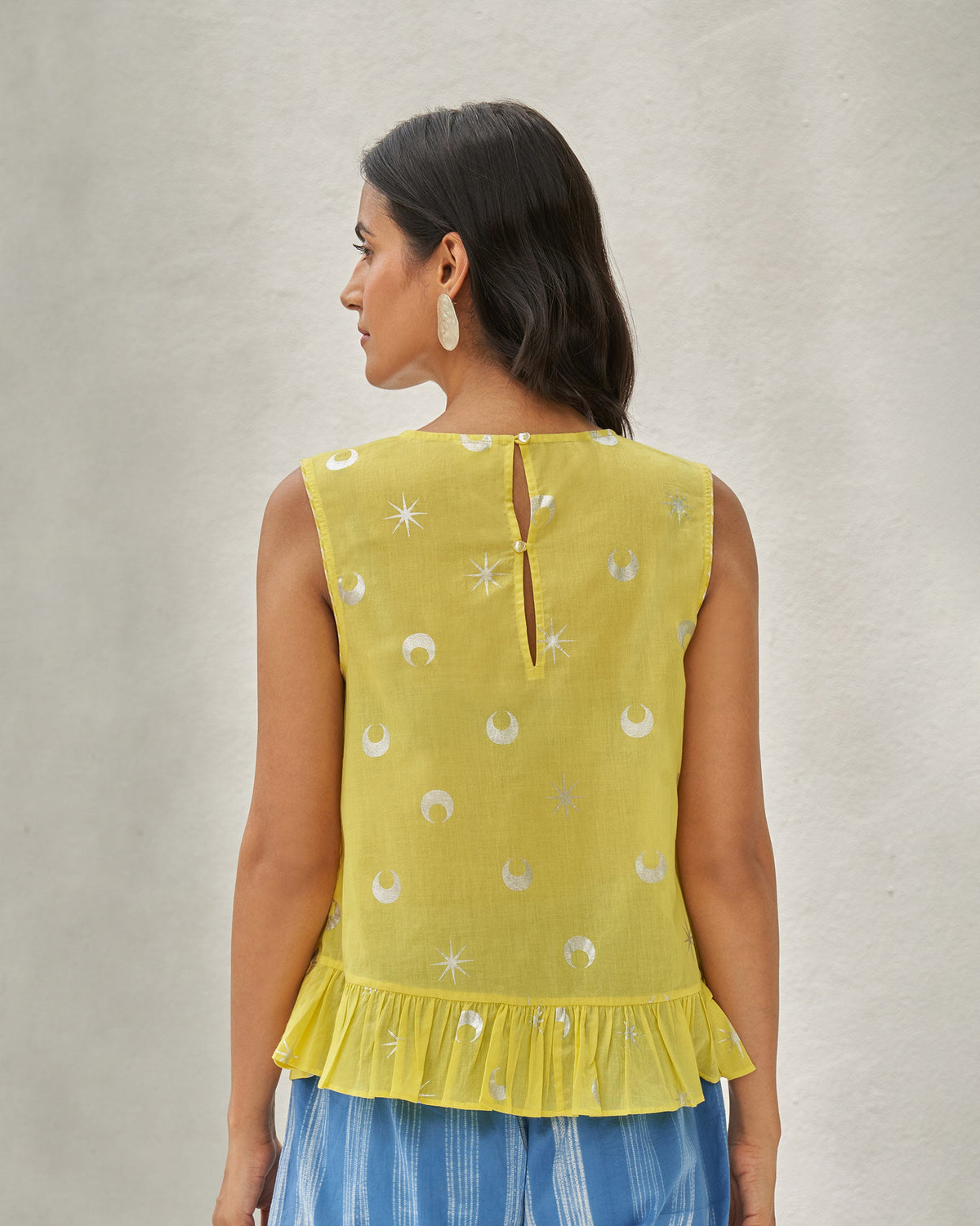 Back of the Demi Moon Ruffle Top worn by a person, with a ruffled hem.