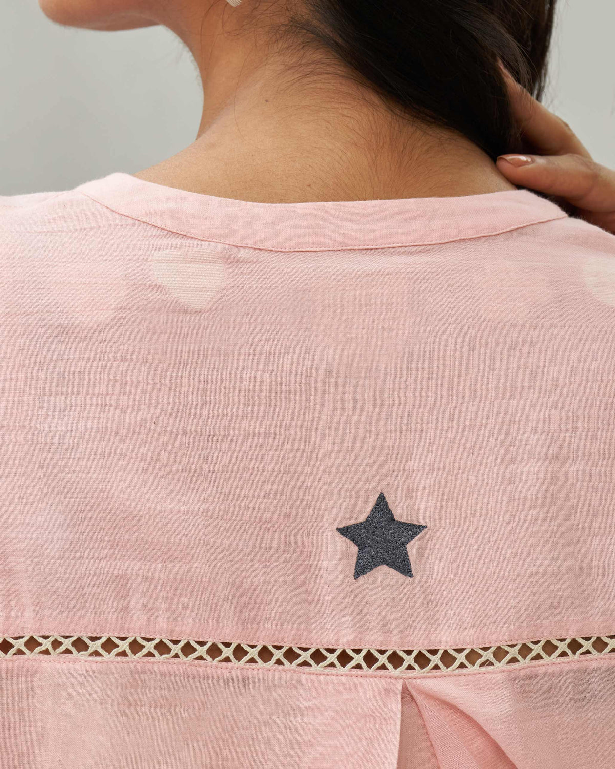 Close-up of the pink Lazy Sunday tunic back with a dark star embroidery and lattice trim.