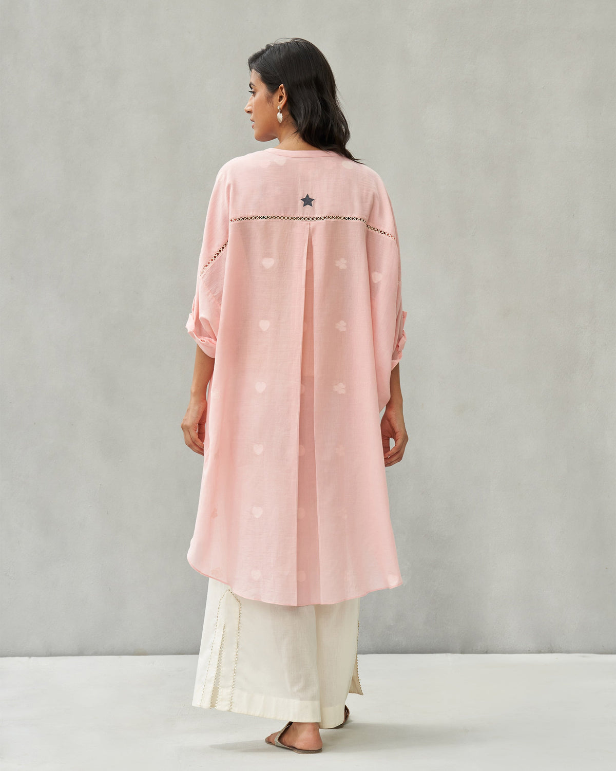 Back of a pink Lazy Sunday tunic with a dark star embroidery, worn by a person.