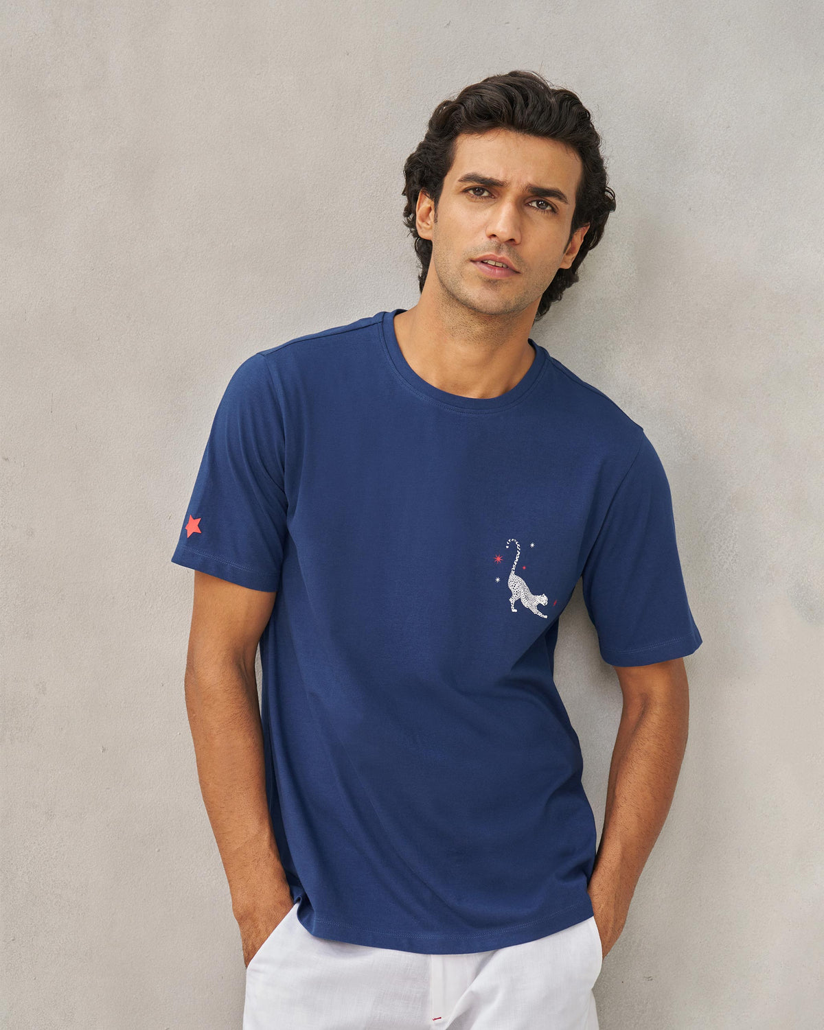 Person wearing a navy Party Cheetah T-shirt with a cheetah motif on the chest and a red star on the sleeve.