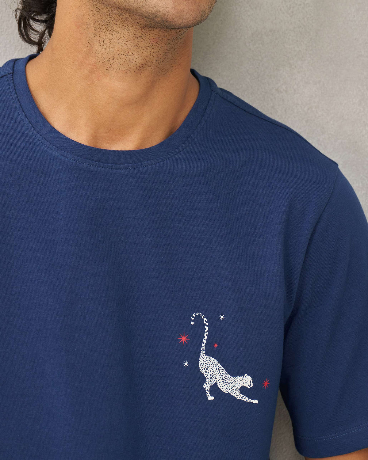 Close-up of a navy Party Cheetah T-shirt chest with a white cheetah motif and red stars.