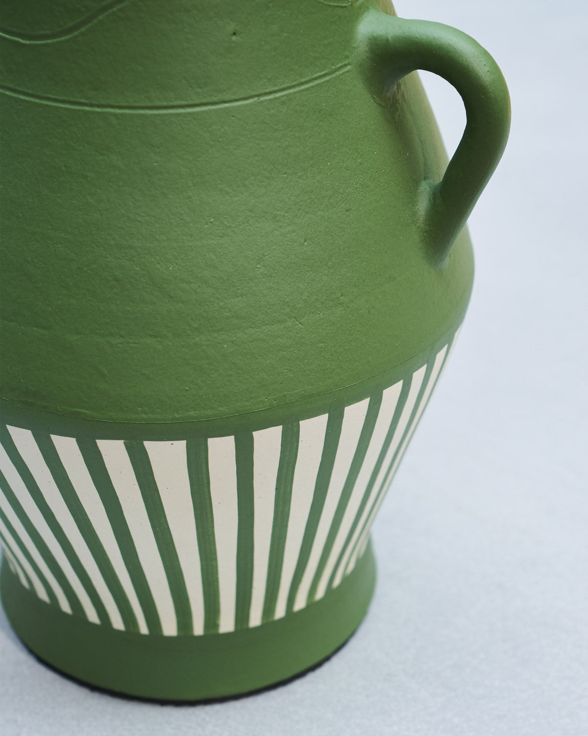 Close-up of Moss Vase showing a green handle and cream striped base.