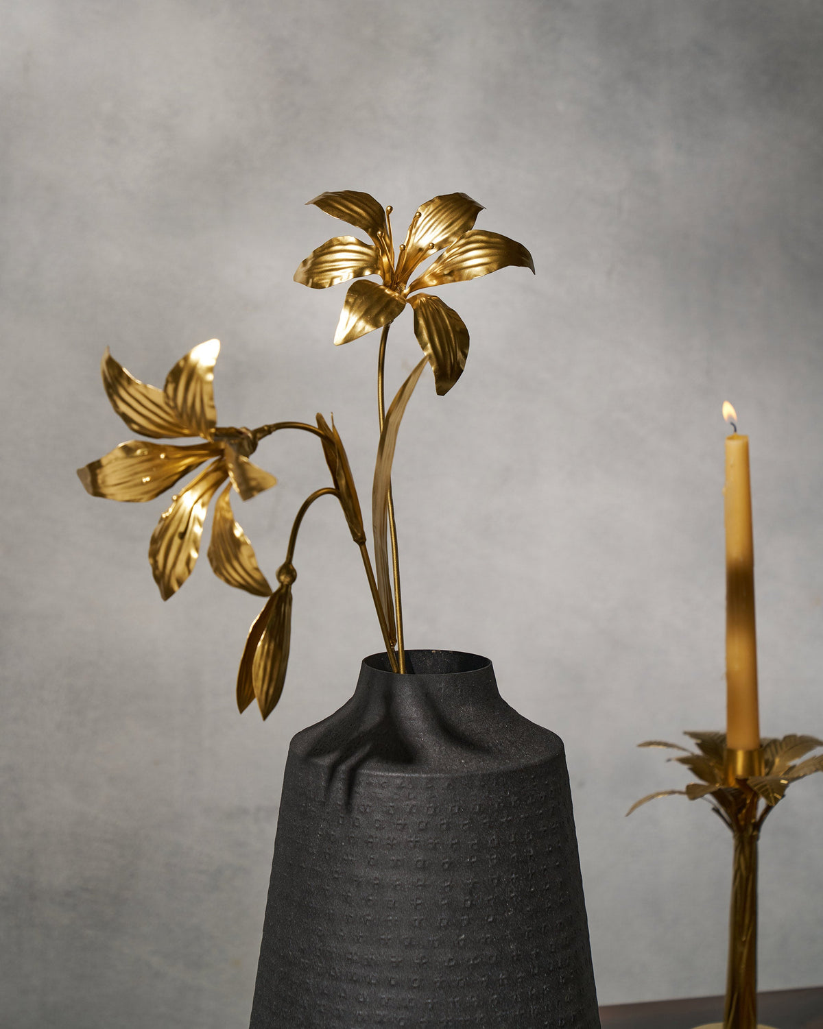 Gold Amaryllis accent stems with open blooms and a bud in a black vase.