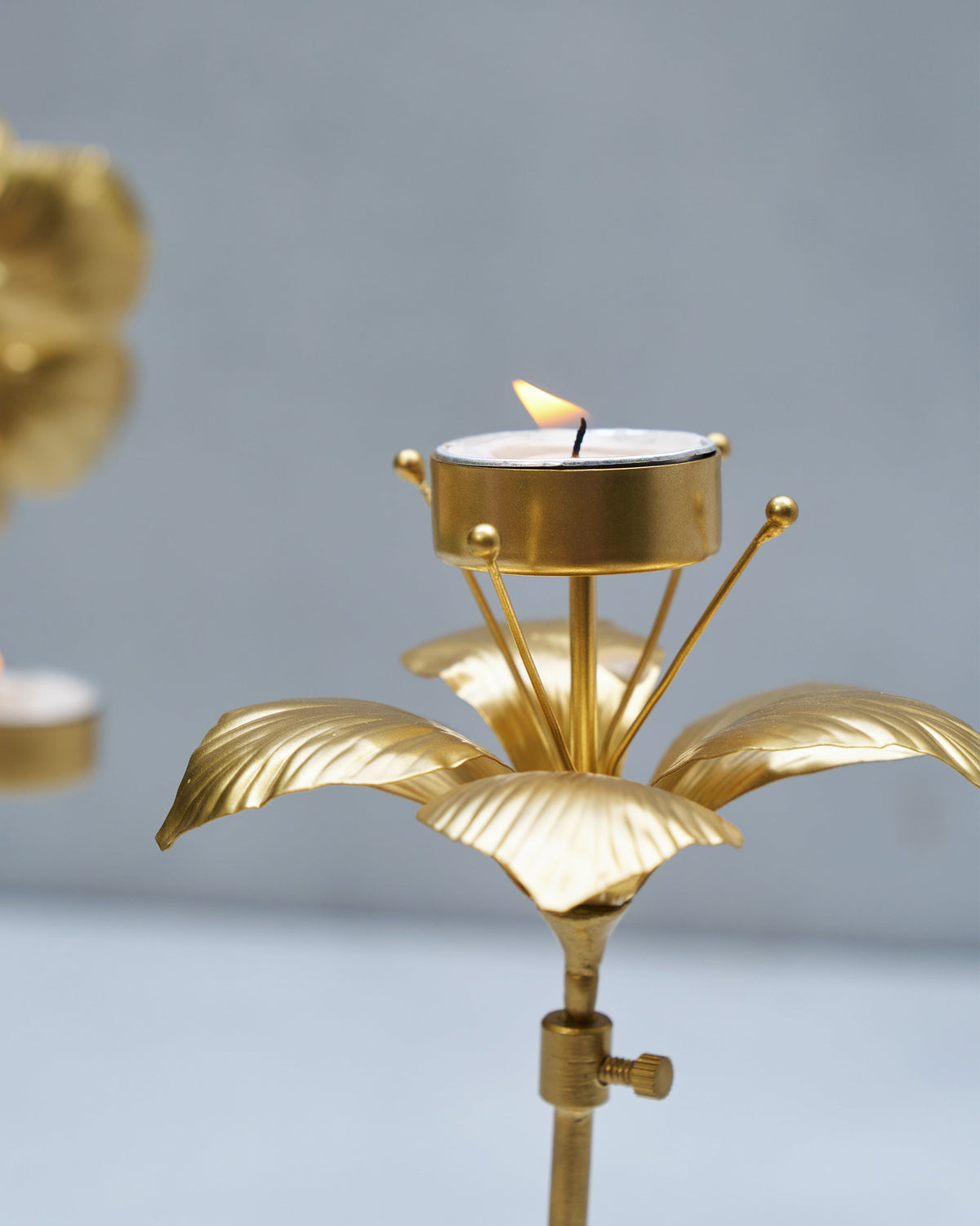 Close-up of a gold Amaryllis Bloom Tealight Holder with a lit tealight.