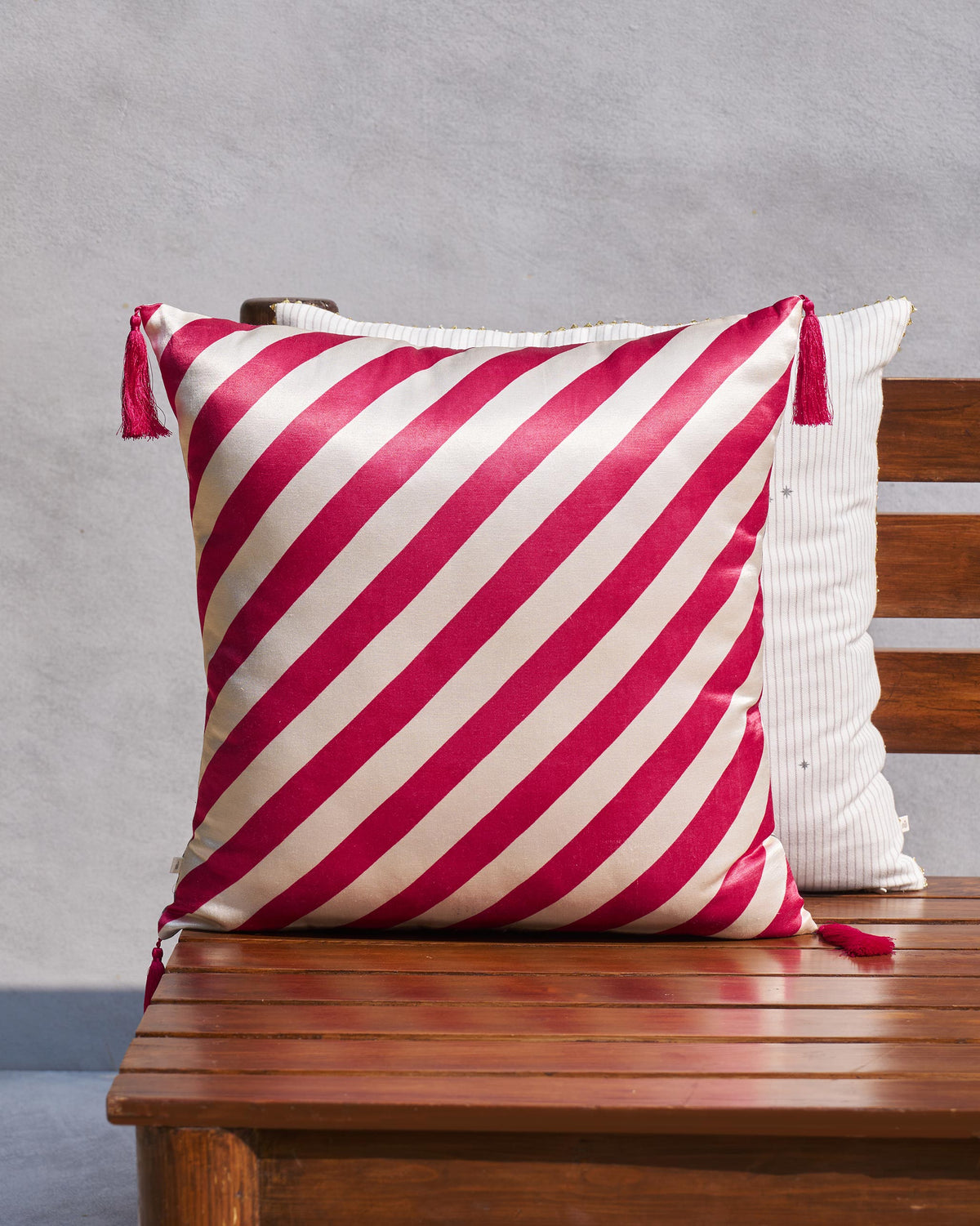Red and cream diagonal striped cushion cover with tassels at two corners.