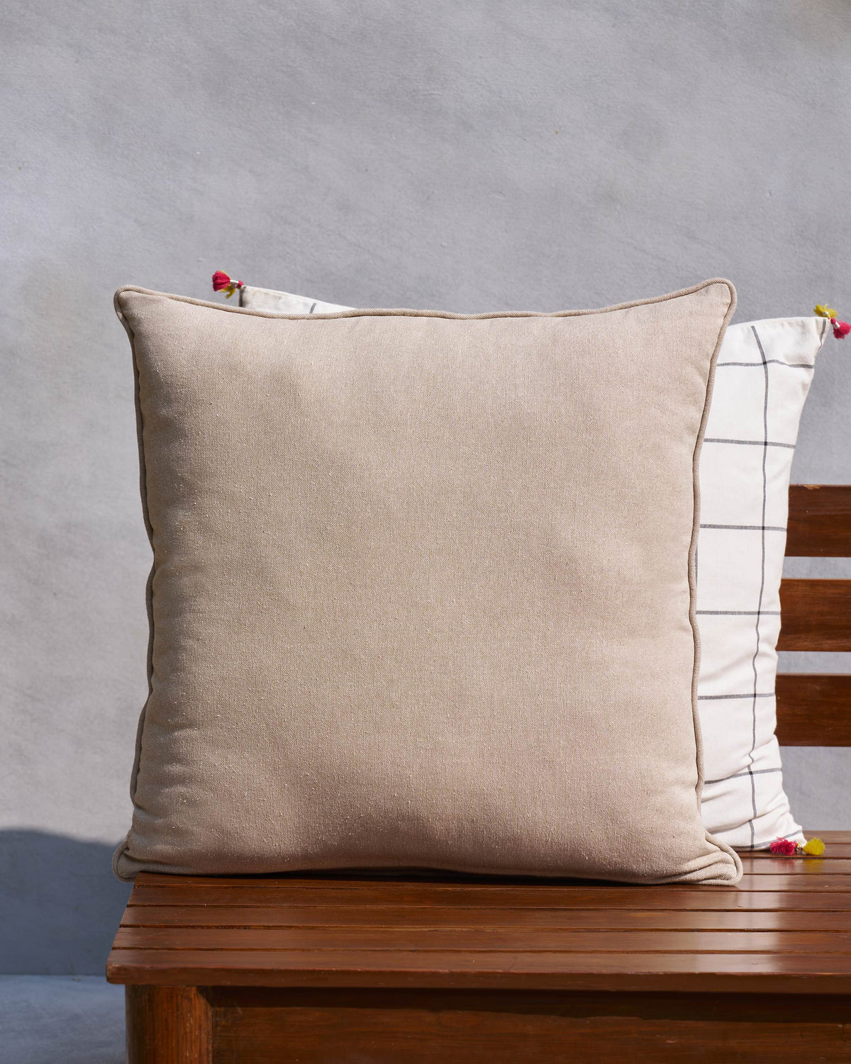 Plain beige cushion cover on a wooden bench.