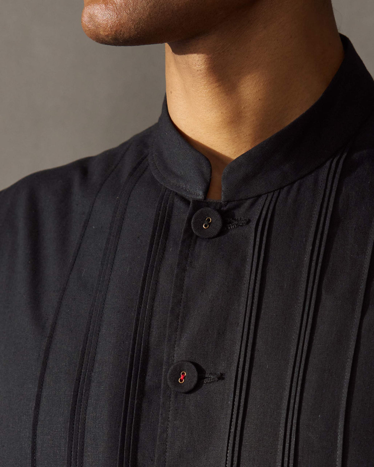 Close-up of a black Short Bandhgala Jacket showing its band collar, pleated placket and buttons.