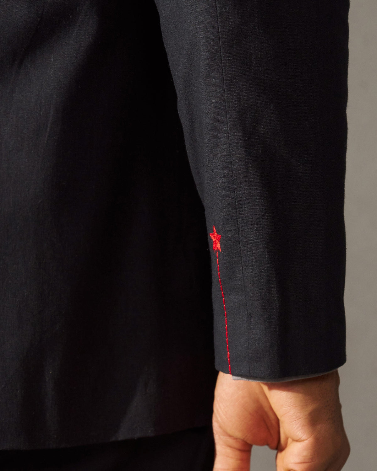 Close-up of a black Short Bandhgala Jacket sleeve with red topstitching and a small red embroidered accent.