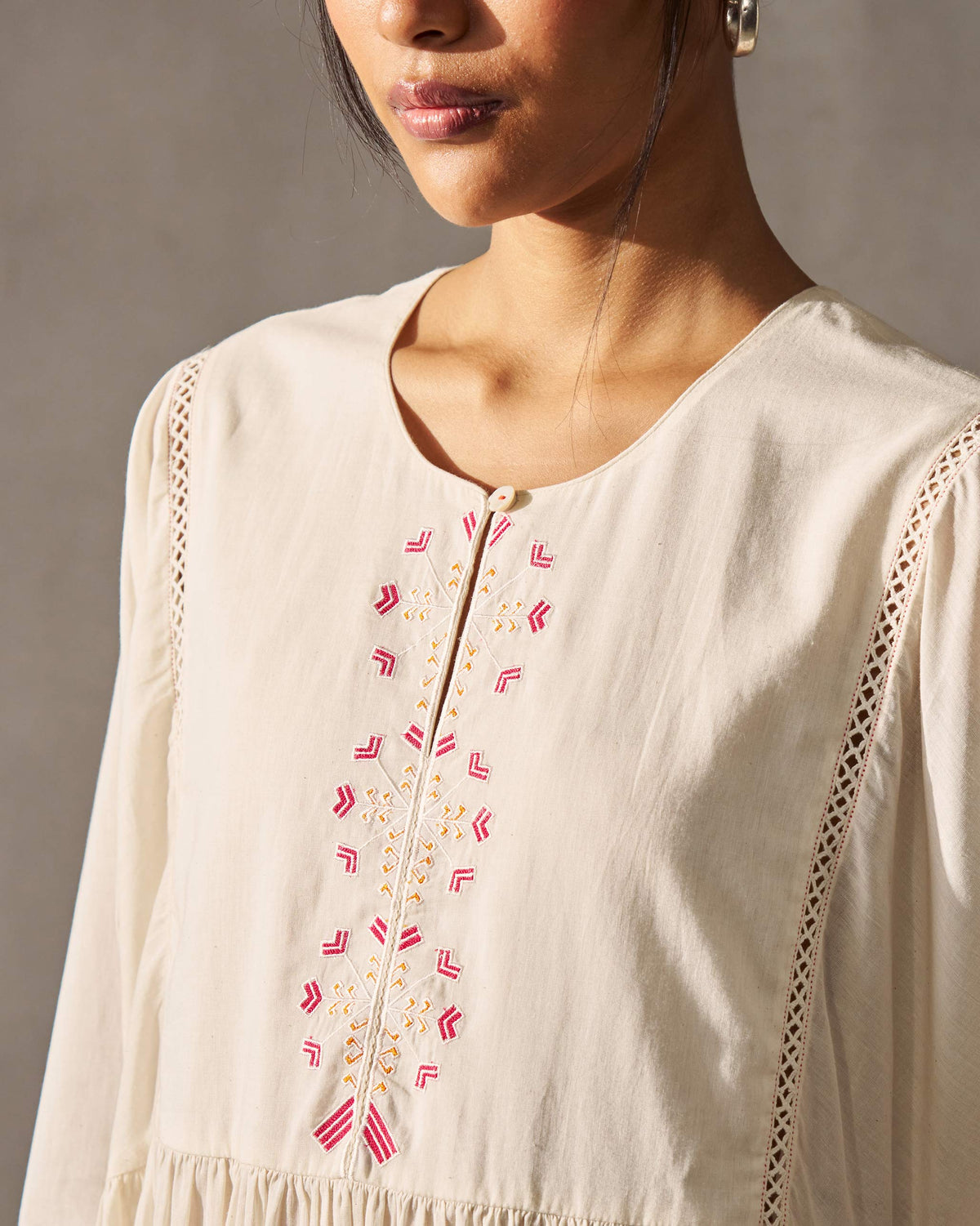 Close-up of an ivory Sara Gathered Kurta showing pink and gold embroidery down the placket.