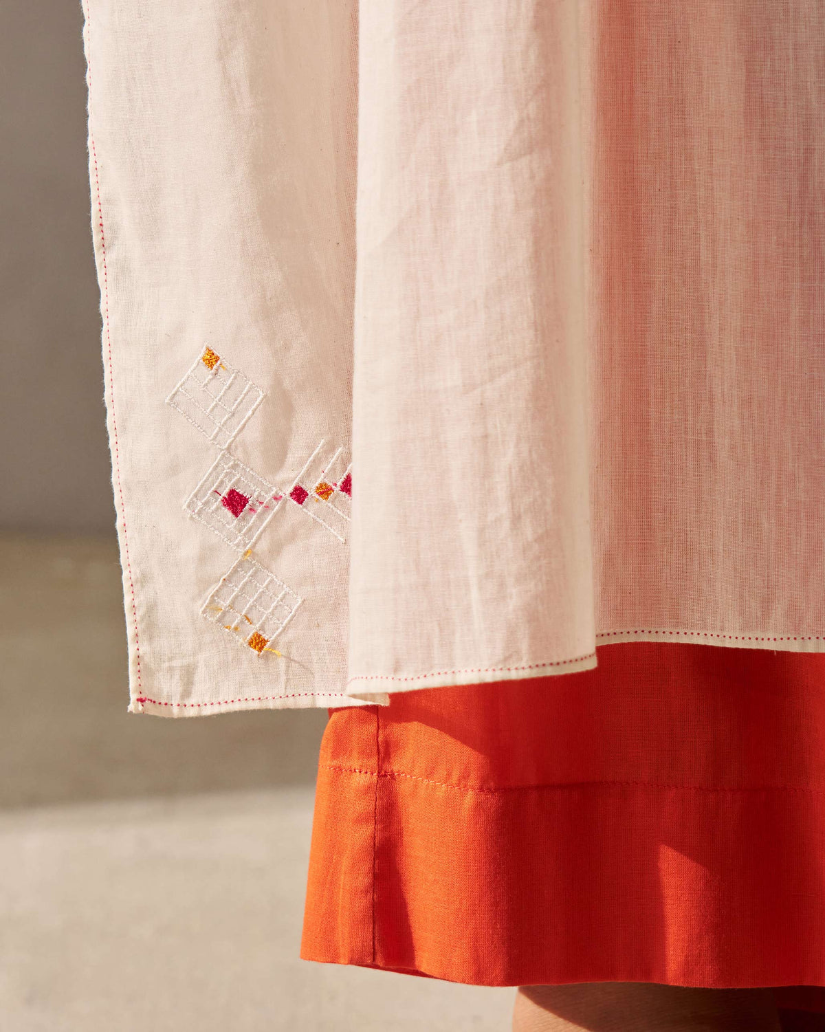 Close-up of an ivory Sara Gathered Kurta hem with a white embroidered motif on the edge.