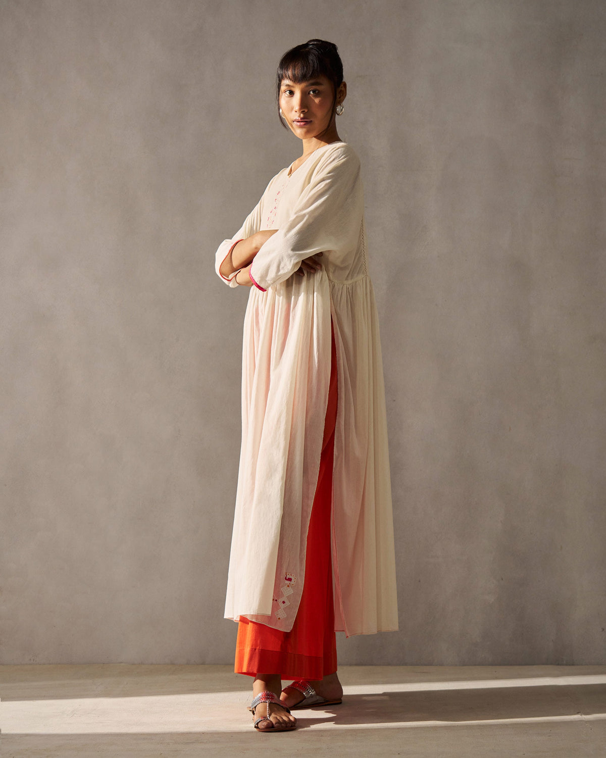 Side view of an ivory Sara Gathered Kurta with a gathered waist and side slits.