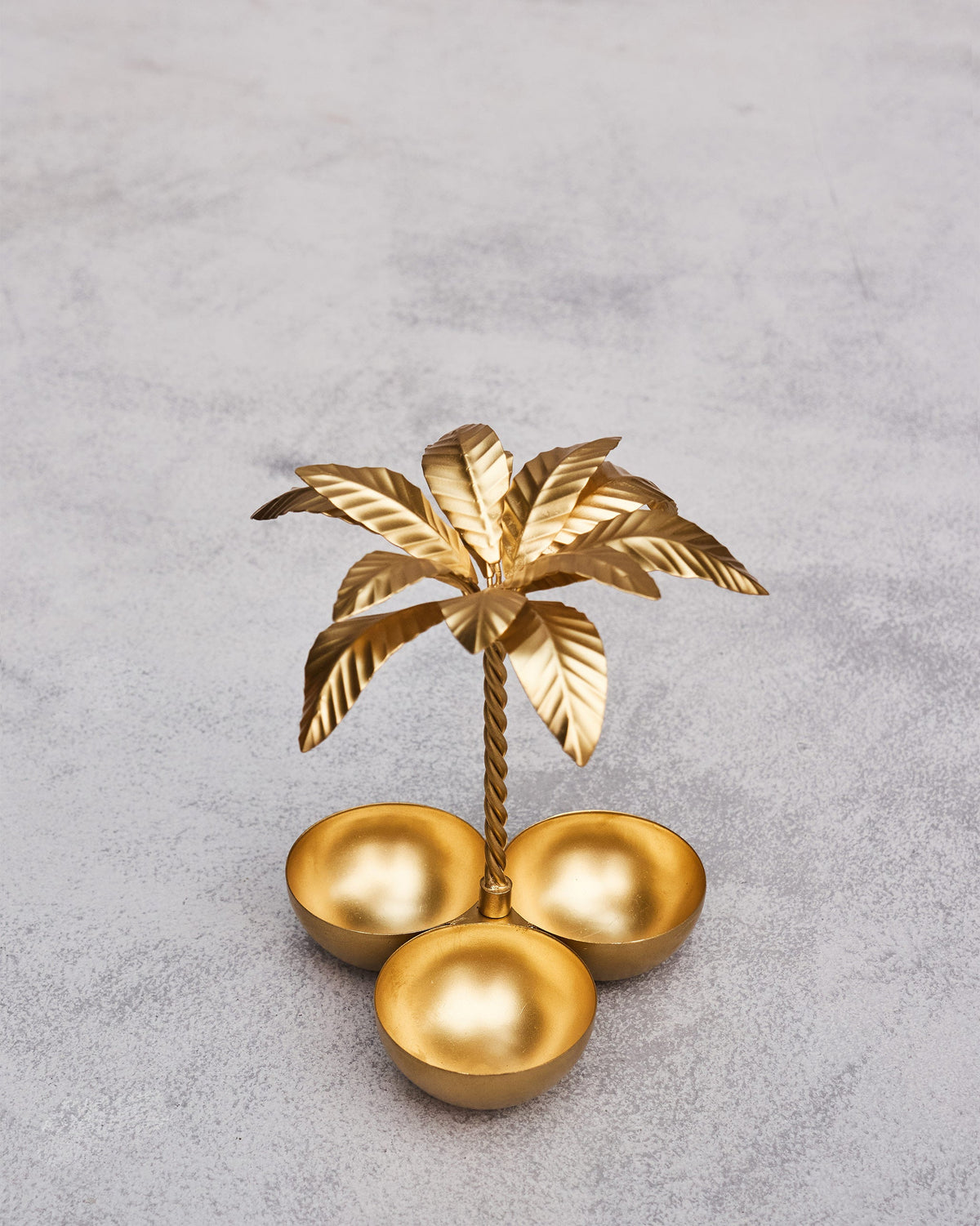 Palm Trinket Tray from above, with three gold bowls around its stem.