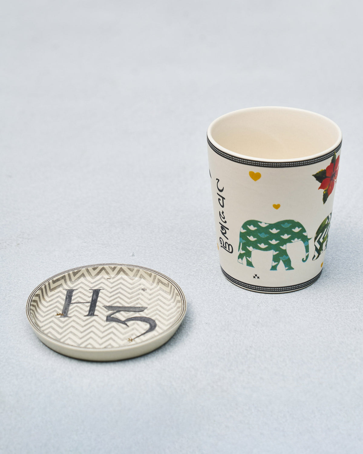 H Alphabet cup with elephant and hibiscus motifs beside a letter H coaster.