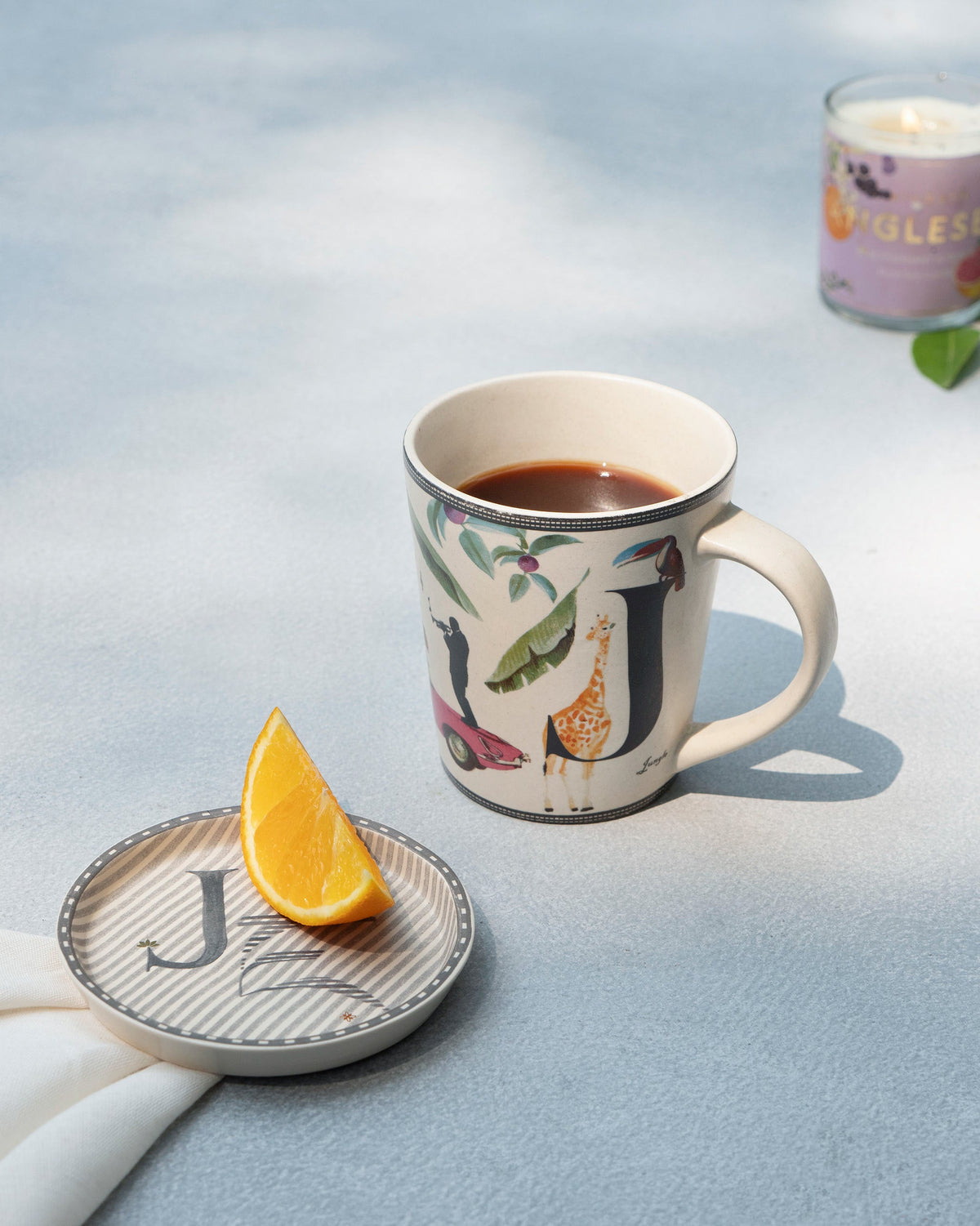 J Alphabet mug filled with coffee beside a matching letter J coaster.