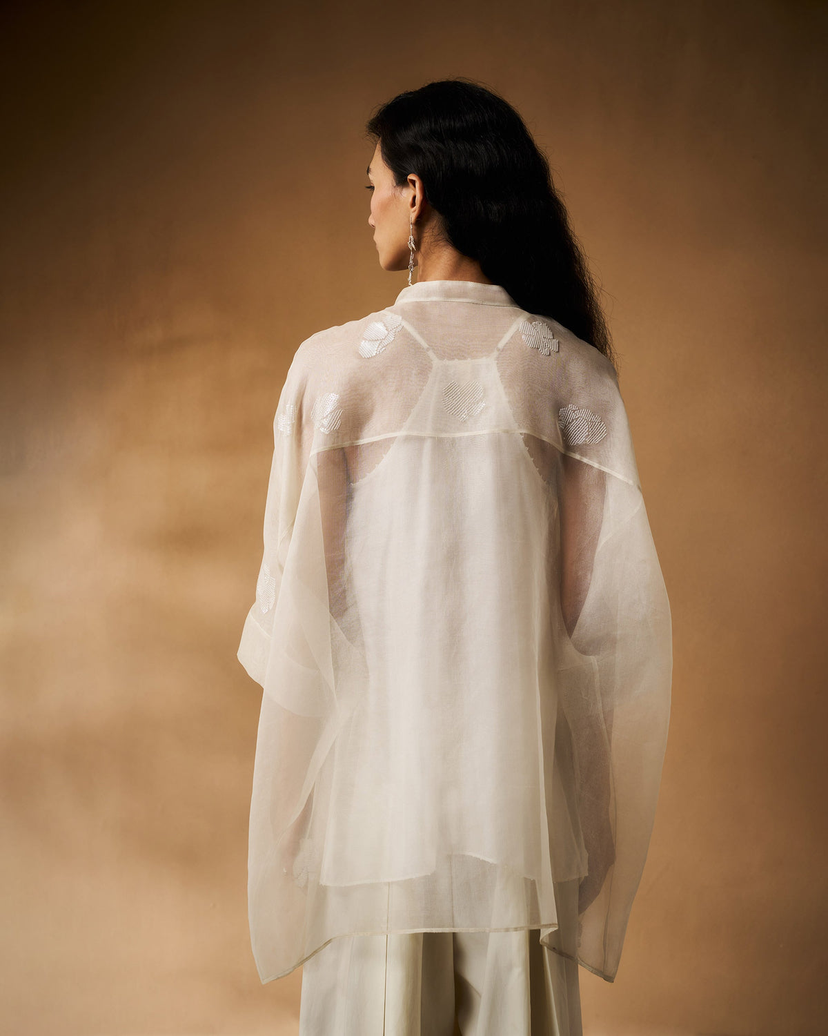 Back of an ivory Afra shirt worn by a person, with embroidered flowers on the shoulders.