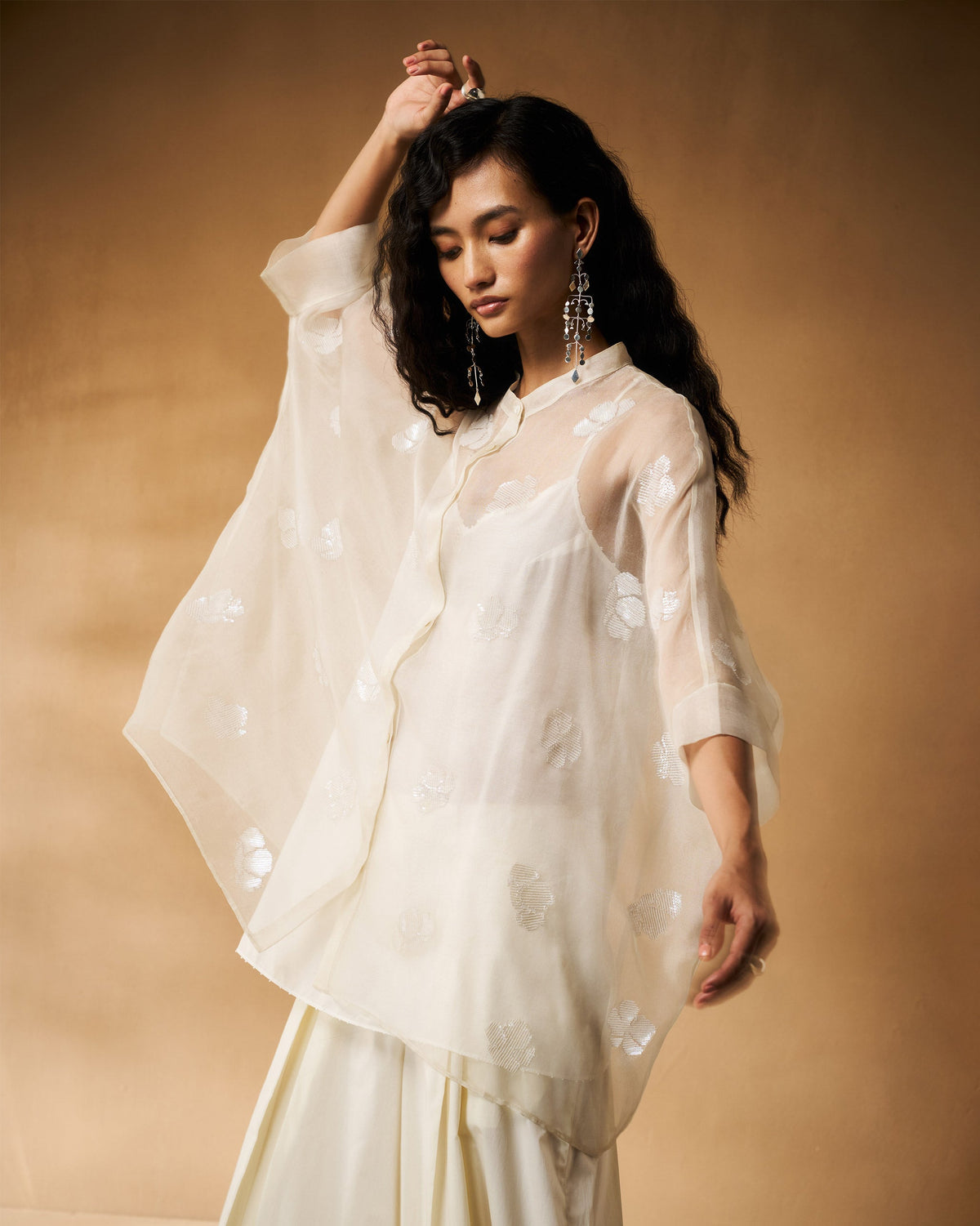 Person wearing an ivory Afra shirt with a sheer organza sleeve draped to the side.