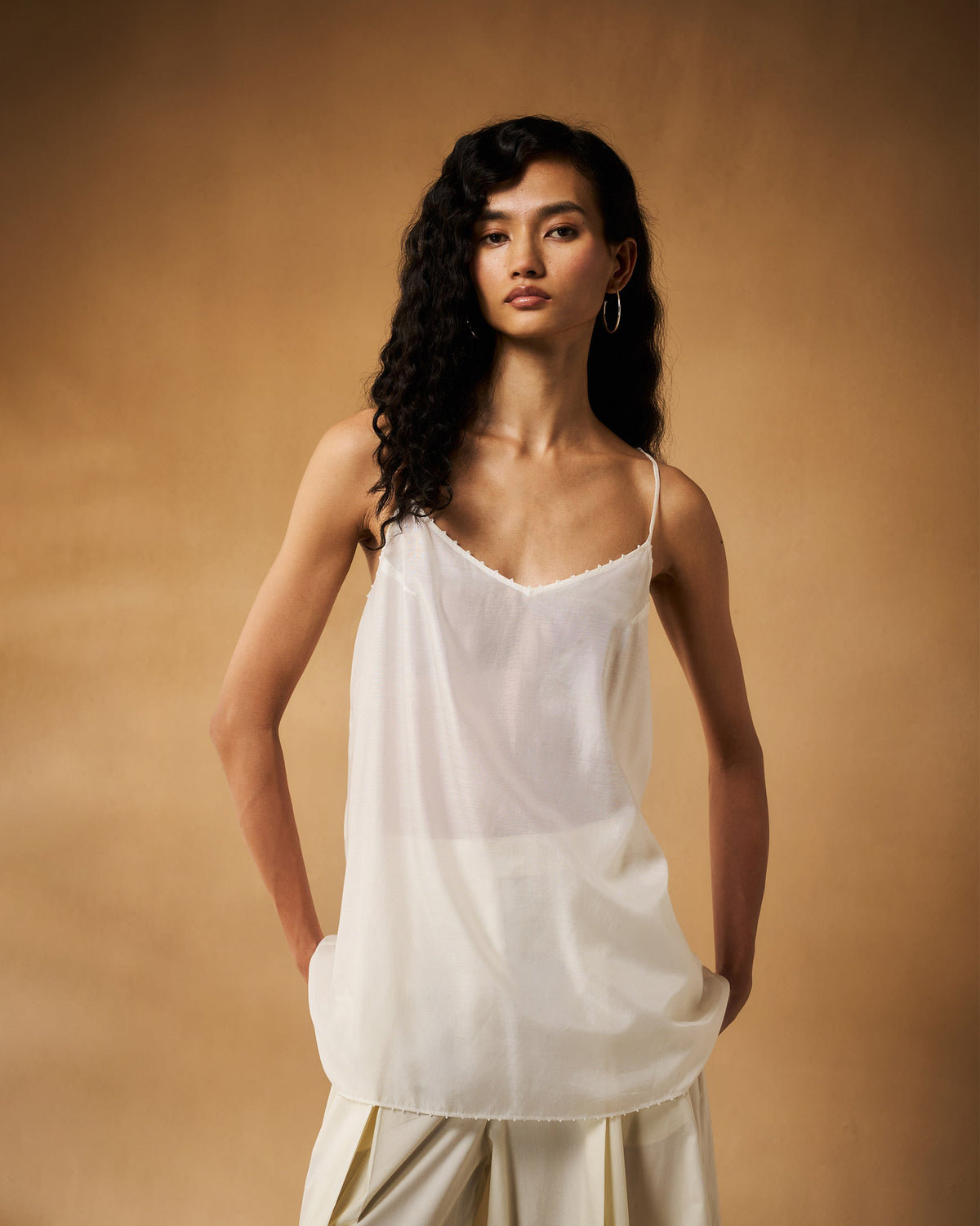 Person wearing an ivory Afra camisole with thin straps and a beaded edge.