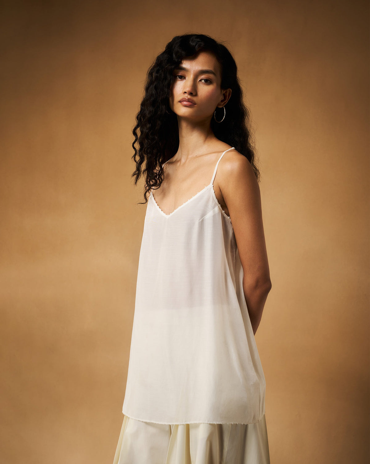 Side view of an ivory Afra camisole with thin straps and a loose fall.